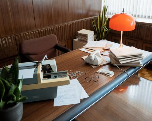 A neat stack of letters and dynamic workplace details on a desk